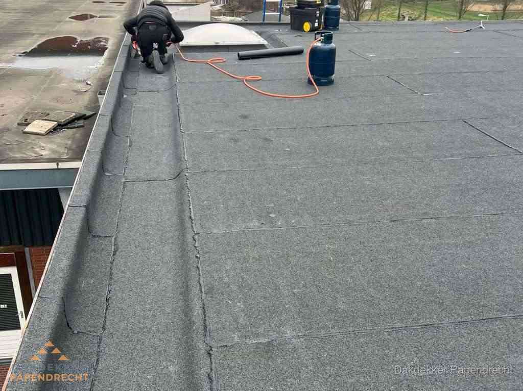 Dakdekker repareert bitumen dakbedekking op groot plat dak in Papendrecht